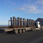 Heavy transport truck carrying metal beam components, highlighting rising logistics and transportation costs in construction.