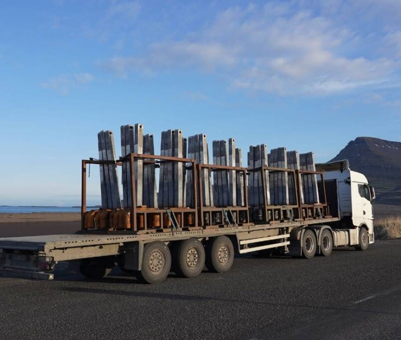 Heavy transport truck carrying metal beam components, highlighting rising logistics and transportation costs in construction.