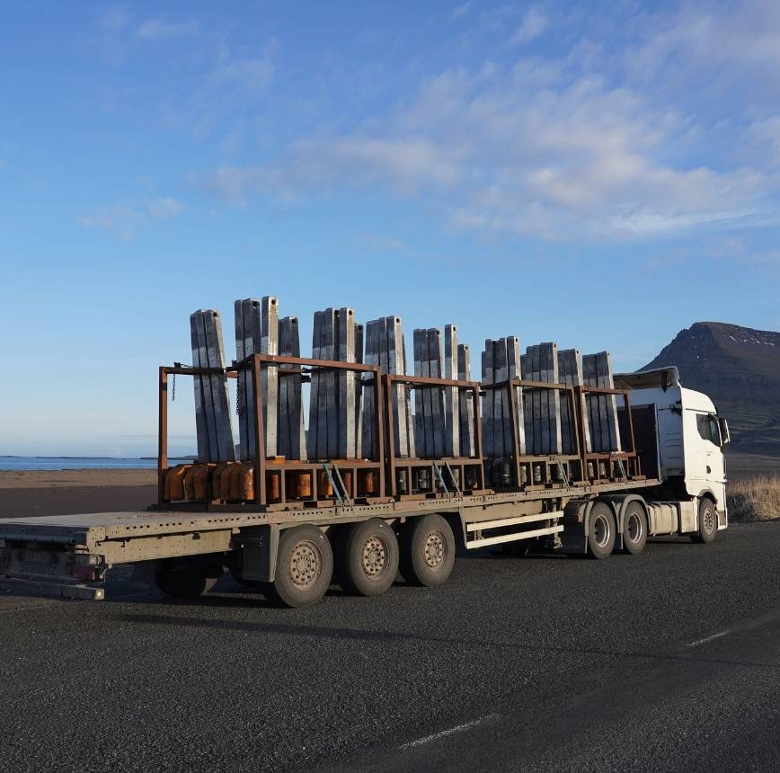 Heavy transport truck carrying metal beam components, highlighting rising logistics and transportation costs in construction.
