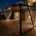 Modern black metal Pergola with integrated LED strip lights on V-shaped posts at night in Ajman.